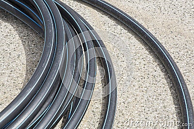 Black polyethylene pipes on a urban road of a construction site with new hydraulic system of drinking water to be carried out Stock Photo