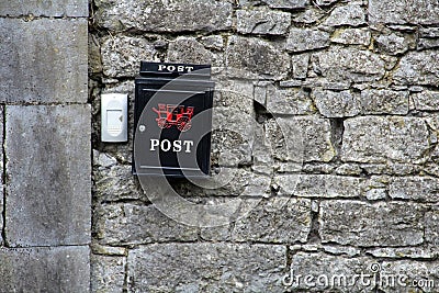 Black Postbox on a stone wall Stock Photo