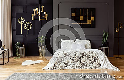 Black poster on grey wall above bed with white pillows in dark bedroom interior with plants. Real photo Stock Photo