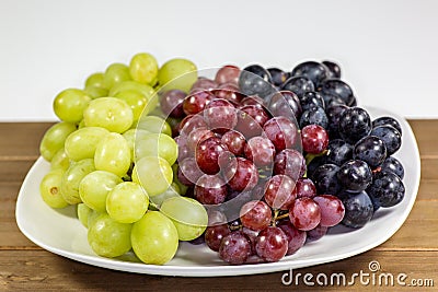 Black, red, green seedless grapes in a deep white bowl Stock Photo
