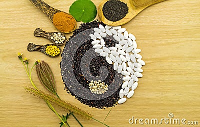 Black rice and white pill forming a yin yang symbol and Spa herbal compressing ball , turmeric powder , millet , soybean , basil s Stock Photo