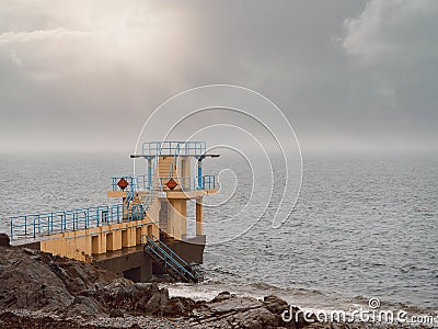 Black rock diving tower, Salthill beach, Galway bay, Dramatic stormy sky over the ocean`s water Stock Photo