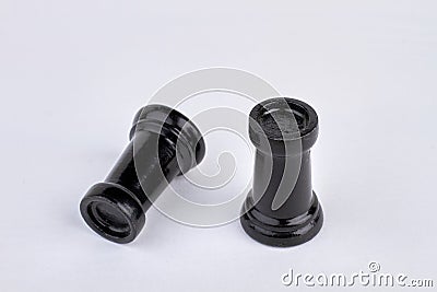 Black rook chess piece stands near fallen chess piece. Stock Photo