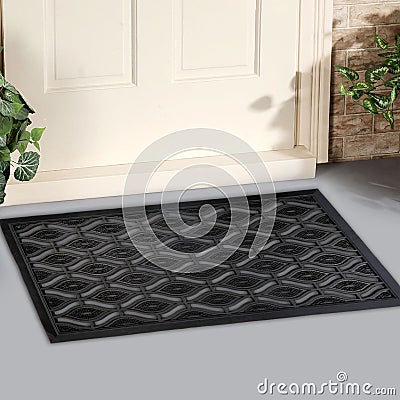 Black Rubber Ellipse Design Eyes Floor Door Mat outside home with yellow flowers and leaves Stock Photo