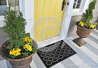 Black Rubber Ellipse Design Eyes Floor Door Mat outside home with yellow flowers and leaves Stock Photo