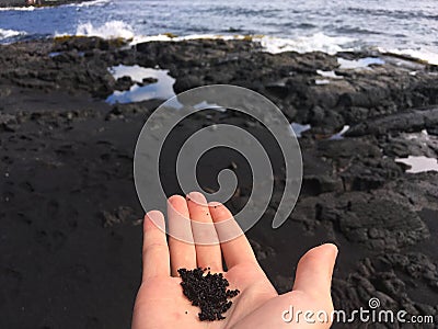 Black sand held in hand Stock Photo