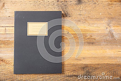 Black school notebook or diary, old fashioned, on wooden background, blank label, space for text, top view Stock Photo