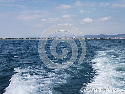 Black sea surface summer wave background. View from yacht. Exotic seascape with clouds and town on horizon. Sea nature tranquility Stock Photo