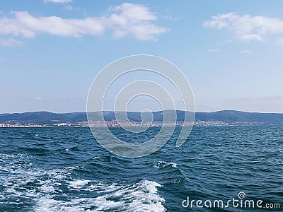 Black sea surface summer wave background. View from yacht. Exotic seascape with clouds and town on horizon. Sea nature tranquility Stock Photo