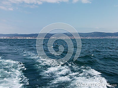 Black sea surface summer wave background. View from yacht. Exotic seascape with clouds and town on horizon. Sea nature tranquility Stock Photo