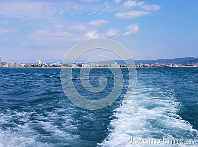 Black sea surface summer wave background. View from yacht. Exotic seascape with clouds and town on horizon. Sea nature tranquility Stock Photo