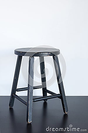 Black shabby stool on wooden surface Stock Photo