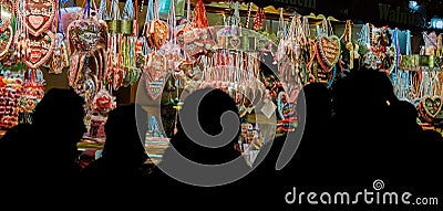 Black shilouettes of people in front of the gingerbread heart stall at the Braunschweig Christmas Market at night Editorial Stock Photo