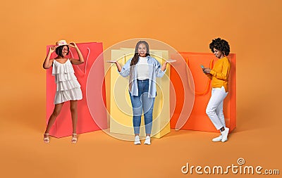 Black shopaholics women posing by giant shopping bags, studio, collage Stock Photo