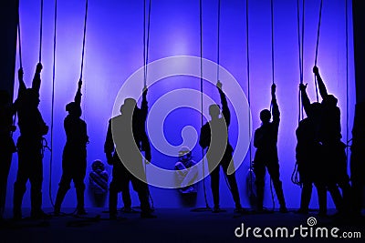 Black silhouettes of people with ropes in their hands at the theater, Shadow play Editorial Stock Photo