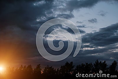 Black silhouettes trees, storm clouds with light breaking through from sun at sunset Stock Photo