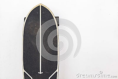 Black skateboard is placed on a white cement wall Stock Photo