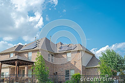 Black solar panels on shingle roofing of two story suburban residential house under sunny cloud blue sky in Flower Mound, Texas, Stock Photo