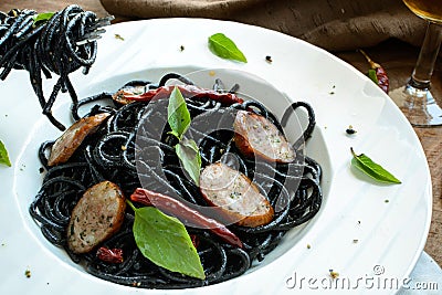 Black spicy spaghetti with sausage and chilli Stock Photo