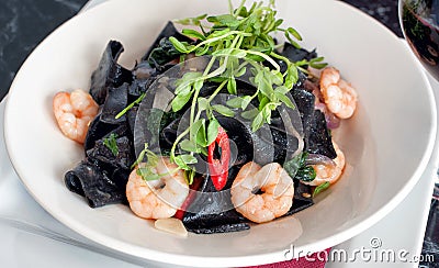 Black squid ink pasta with prawns and chili Stock Photo