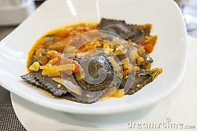 Black squid ink ravioli with natural tomatoes sauce Stock Photo