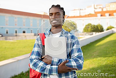 black student guy with backpack, laptop and workbooks posing outside Stock Photo