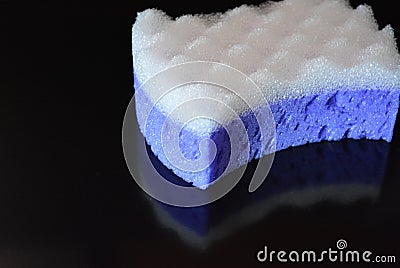 On a black stylish glossy background is a female purple sponge for a body of purple and white with reflection Stock Photo