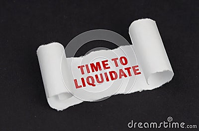 On a black surface lies a white twisted paper with the inscription - Time to Liquidate Stock Photo