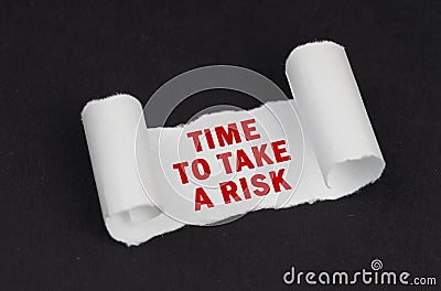 On a black surface lies a white twisted paper with the inscription - Time to Take a Risk Stock Photo