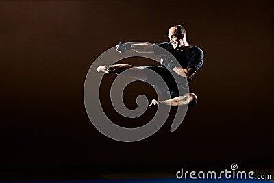 In a black T-shirt, an adult athlete beats a kick in a jump Stock Photo