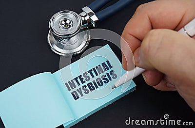 On a black table is a stethoscope and a notebook in which the man wrote - INTESTINAL DYSBIOSIS Stock Photo