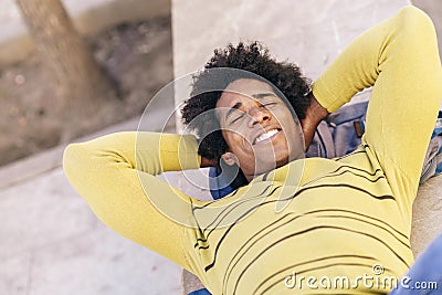 Black tourist with afro hair lying on the ground outdoors. Stock Photo