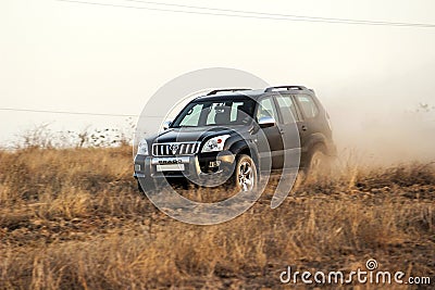 Black Toyota Prado SUV rides in the field in the rays of the sunset Editorial Stock Photo