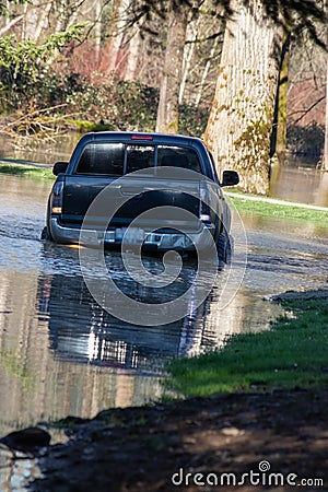 A black truck driving through a flood Stock Photo