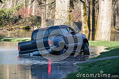 A black truck driving through flooded park Stock Photo