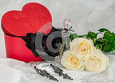 Black underwear knickers in gliter red box heart shaped perfume white roses juwelery on white background Stock Photo