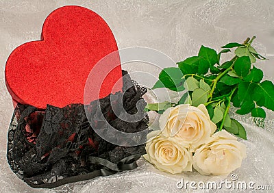 Black underwear knickers in gliter red box heart shaped white roses on white background Stock Photo