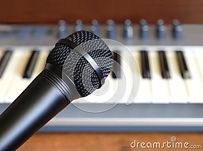 Black vocal microphone closeup against electronic synthesizer keyboard Stock Photo