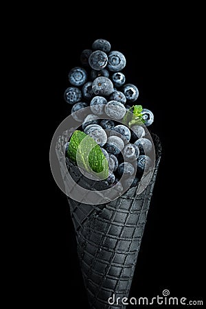 Black wafer cone with frozen blueberry fruits. Ice cream Stock Photo