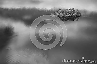 Black and white Abstract landscape Autumn image of view of islands in Derwentwater with sky reflections isolating them with deep Stock Photo