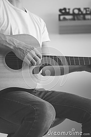 Black and white candid portrait of an artist strumming a guitar at home. He enjoys every chord played. Close-up on a hand playing Stock Photo