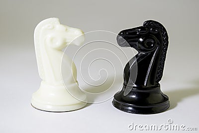 Black and white chess horses stand opposite each other on a white background, tight shadow Stock Photo