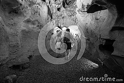 Black and white. Couple of tourists exploring the cave. The interior of the cave. Touristic hiking route. Concept of excursions Stock Photo