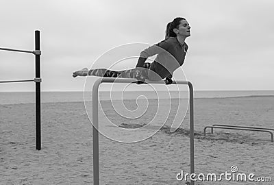 Black and white fitness woman doing hand stand exercises on callisthenics outdoor gym bars.Beach workout, street sports training Stock Photo