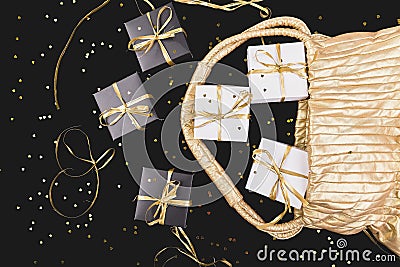 Black and white gift boxes with gold ribbon pop out from golden bag Stock Photo