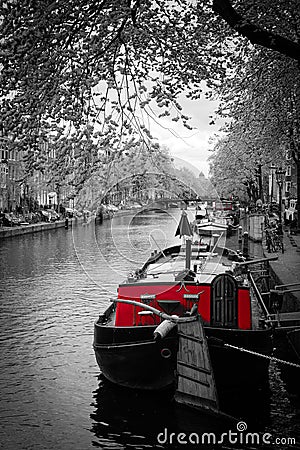 Black and white image of an amsterdam canal with red tug boat Stock Photo