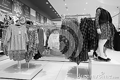 Black and White image of Children clothes hanging on hangers in the shop. Colourful kid blouses and shirt hanging on the cloth Editorial Stock Photo