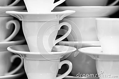 Black and white image of the white cups and saucers arranged in the rows. Stock Photo