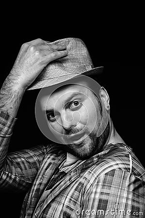 Black and white image handsome tricky stylish bearded man in checkered blazer putting on hat Stock Photo