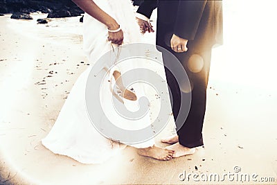 Black and white image of lower half of bride and groom standing barefoot on the sand Stock Photo